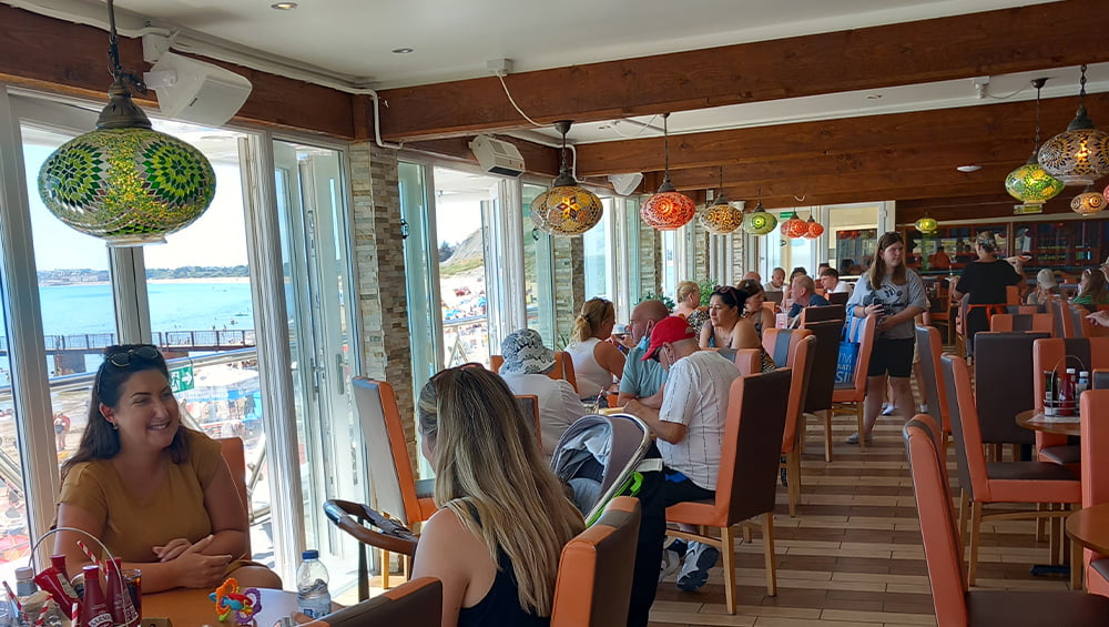 A group of people sitting in a restaurant with a view of the ocean.