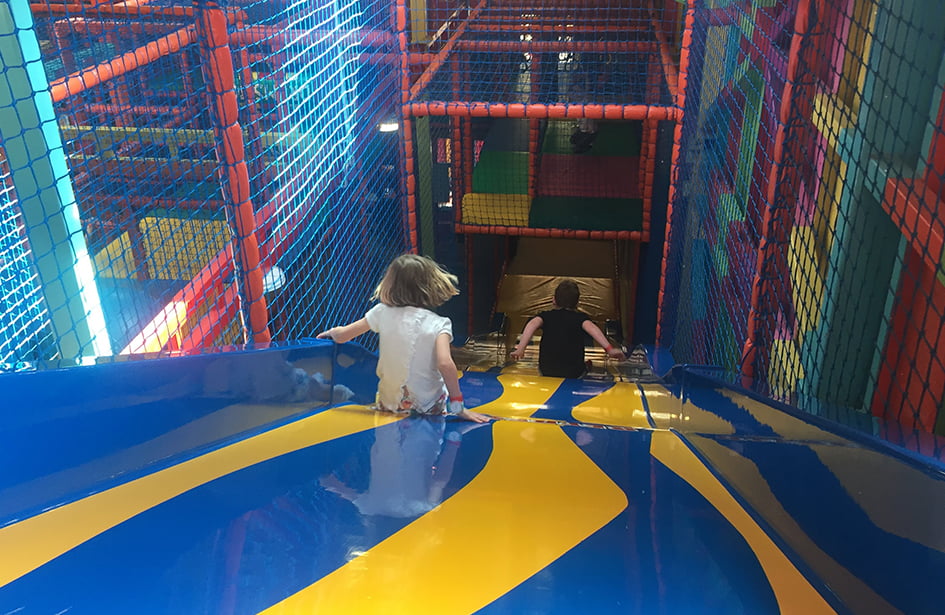A child is walking down a slide in an indoor play area.
