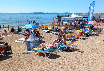 A crowded beach with umbrellas and lounge chairs.