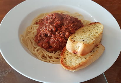 A plate of spaghetti with meat sauce and bread.