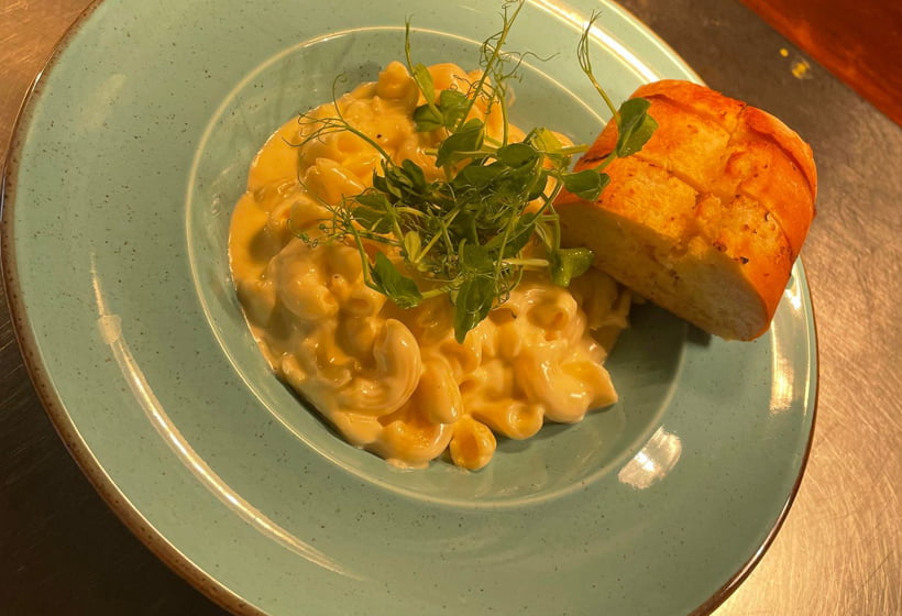 A blue plate with macaroni and cheese on it.