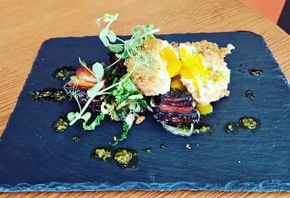 A black slate plate with a dish on it.